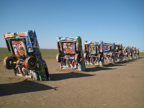 Route 66 - Cadillac Ranch é uma instalação artística com dez automóveis Cadillac, localizada em Amarillo, Texas. Foi criada em 1974 por três artistas participantes de um grupo chamado Ant Farm. Com o tempo, visitantes começaram a grafitá-los e hoje são todos coloridos. Na animação Cars ela é mostrada como uma formação montanhosa; Bruce Springsteen e Chris LeDoux gravaram músicas chamadas Cadillac Ranch; as bandas Supercharge e Atomic Tom gravaram clips nesse lugar - Foto: Reprodução/Wikipedia.